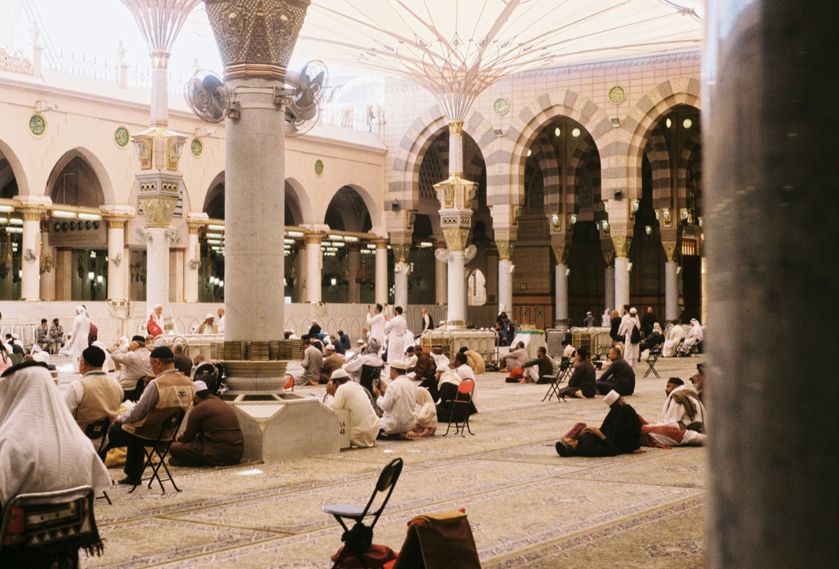 Worshippers seated in the courtyard of the Prophet's Mosque in Madinah, beneath its arches and canopies