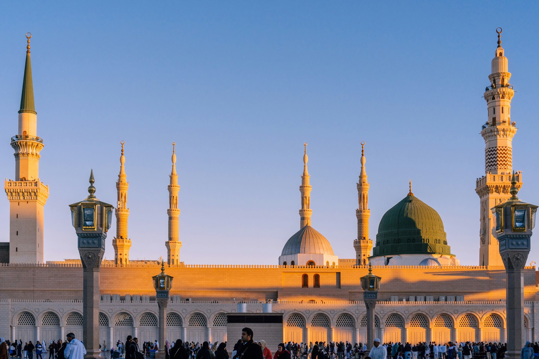 The Prophet's Mosque in Madinah at golden hour, its minarets lit by low sun